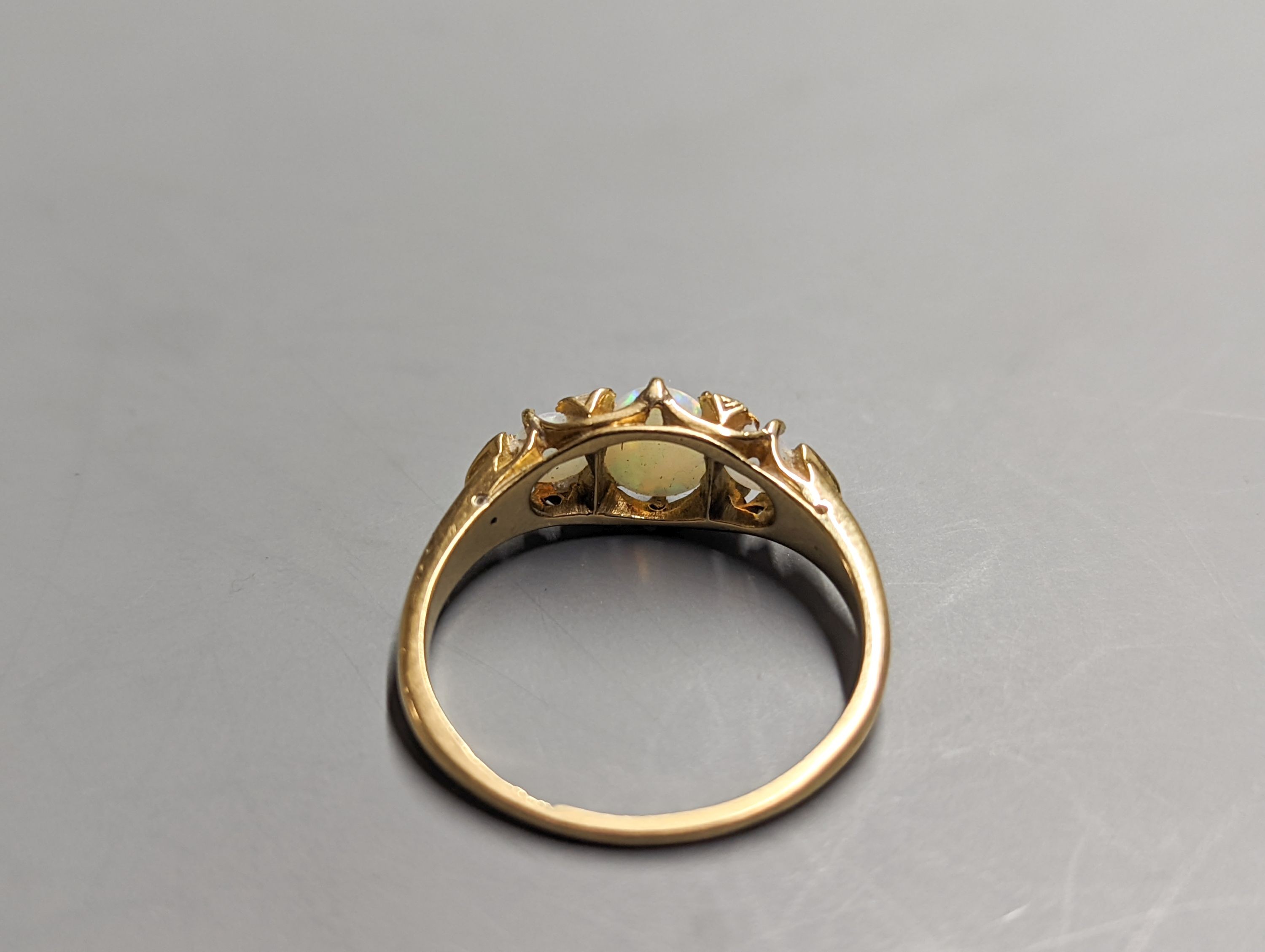 An early 20th century 18ct and three stone white opal set ring, with diamond chip spacers, size Q/R, gross 3.7 grams.